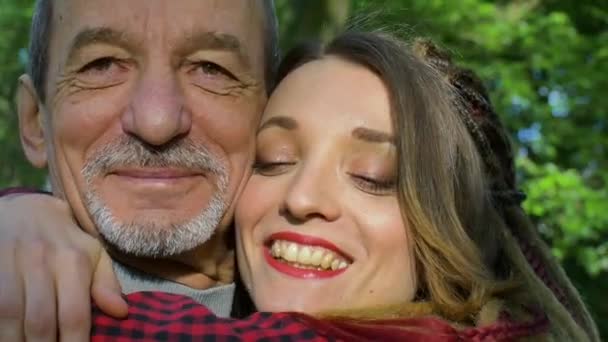 Modernes Mädchen mit Dreadlocks umarmt ihren älteren Vater, der bei schönem Wetter Zeit im Park verbringt. Vatertagskonzept - Filmmaterial, Video