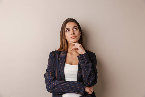 Photo of young businesswoman in formal suit thinking and looking upward isolated over white background - Zdjęcie, obraz