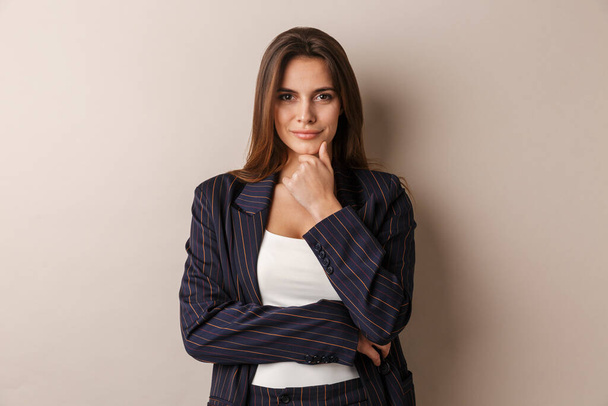 Photo of pleased businesswoman in formal suit posing and looking at camera isolated over white background - Φωτογραφία, εικόνα