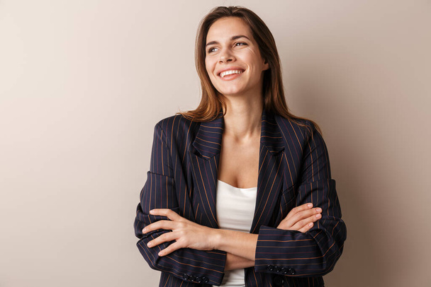 Photo of joyful businesswoman in formal suit laughing with arms crossed isolated over white background - Foto, afbeelding