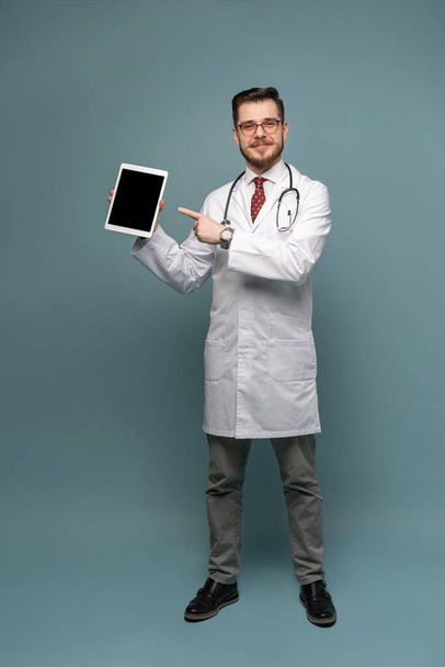 A portrait of a medical doctor posing against gray background - 写真・画像