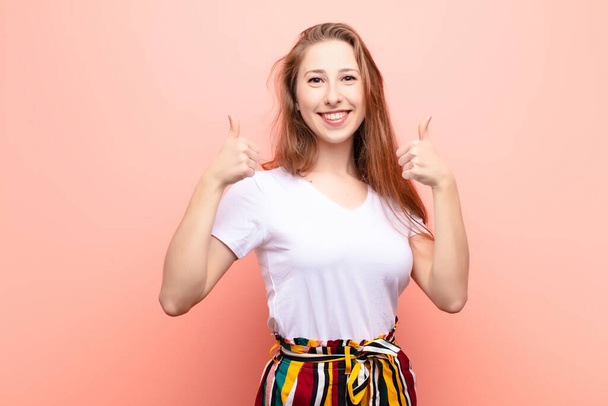 yound blonde woman smiling broadly looking happy, positive, confident and successful, with both thumbs up - Foto, afbeelding