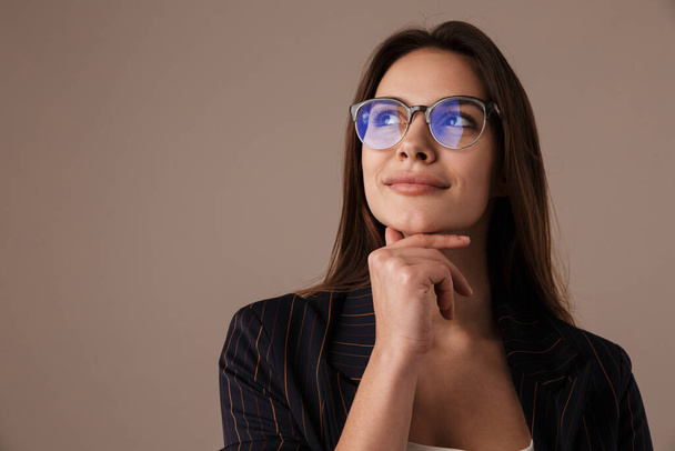 Photo of charming businesswoman in eyeglasses posing and looking upward isolated over grey background - Foto, afbeelding