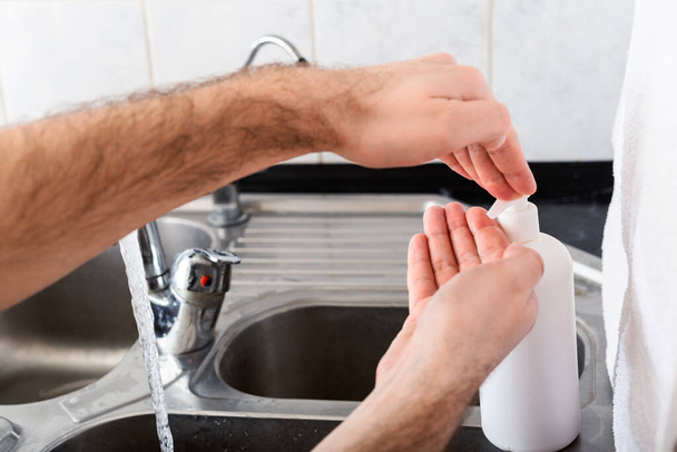 Man washing hands with antibacterial soap and water in metal sink for corona virus prevention. Hand hygiene, health care, medical concept. Hand skin disinfection protect from Coronavirus covid 19 - Foto, afbeelding