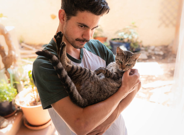 Jovem tem um gato cinzento em seus braços
   - Foto, Imagem