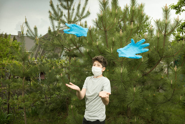 The joy of a young man in the nature after quarantine. Soon a mask and gloves will not be needed. The boy takes off and throws out the gloves. - Photo, Image