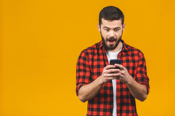Wow, great news! Happy man in casual typing sms on yellow background. - Photo, Image