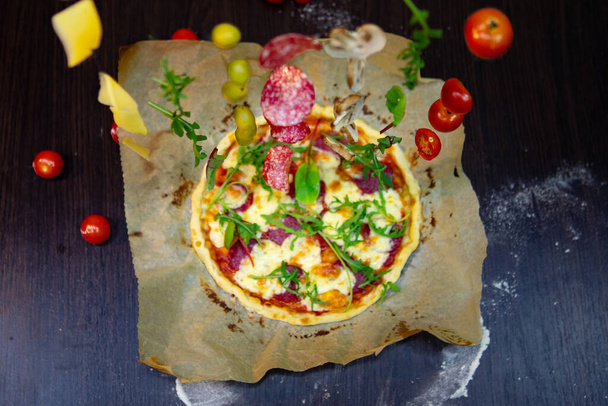 górny widok na pizzę z pomidorami ser sałatka salami gotowanie - Zdjęcie, obraz