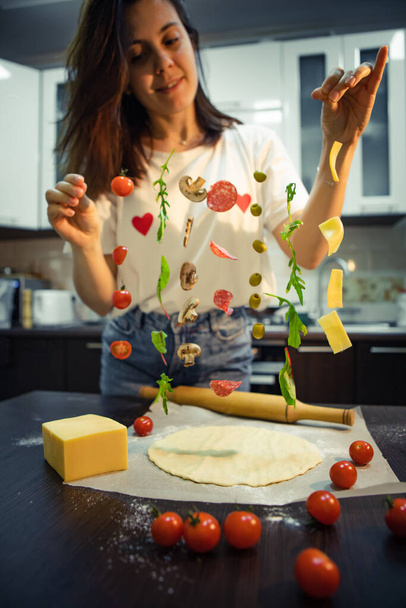 γυναίκα που φτιάχνει συστατικά πίτσας όπως μανιτάρια σαλάμι, τυρί ελιάς παγωμένο στον αέρα. σπιτικό φαγητό - Φωτογραφία, εικόνα
