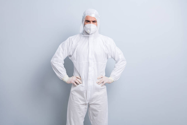 Photo of serious confident guy expert virology center clinic arms by sides visit patient wear face mask hood uniform suit plastic facial protection eyes nose isolated grey color background - Foto, Imagen