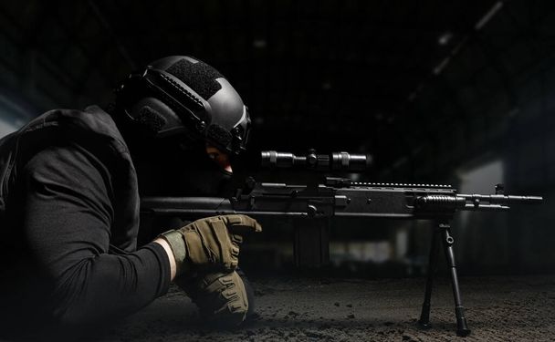 Foto di un soldato in casco e munizioni posa e mira fucile da cecchino profilo vista su sfondo scuro
. - Foto, immagini