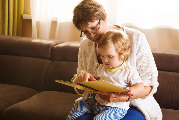 Abuela leyendo un cuento a su nieta bebé. Lectura familiar Ocio
   - Foto, Imagen
