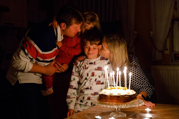 Schattige jongen viert zijn tiende verjaardag. Peuter Baby kind, moeder en vader samen verjaardagskind met taart en kaarsen. Gelukkig gezond familieportret - Foto, afbeelding