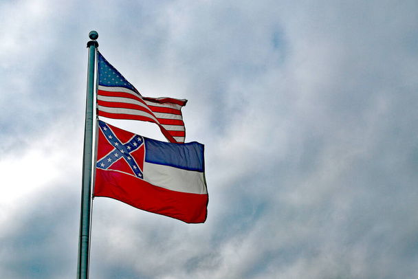 Amerikanische Flagge und Mississippi-Flagge an Fahnenmast wehen im Wind - Foto, Bild
