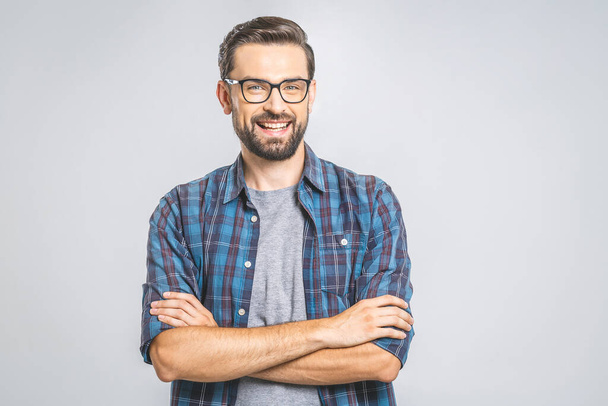 Happy young man. Portrait of handsome young man in casual shirt keeping arms crossed and smiling while standing against grey background - Φωτογραφία, εικόνα