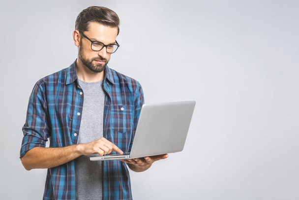 Magabiztos üzleti szakértő. Magabiztos gondolkodó fiatal jóképű férfi ing kezében laptop, miközben áll szemben szürke háttér - Fotó, kép