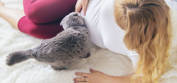 Une femme enceinte avec un chat est couchée au lit. Concentration sélective. animal. - Photo, image