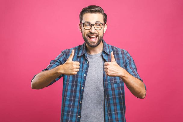 Portrait of young man in glasses showing thumbs up isolated over pink background - Foto, imagen