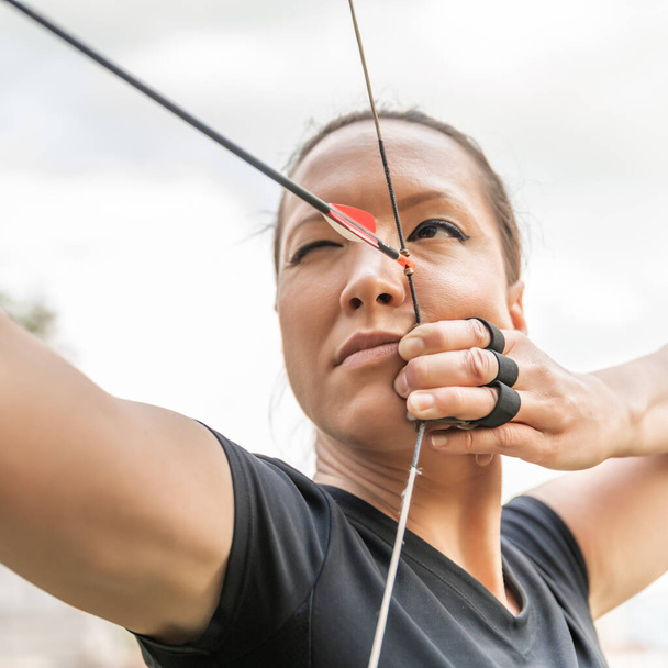 attractive woman on archery, focuses eye target for arrow from bow - Photo, image