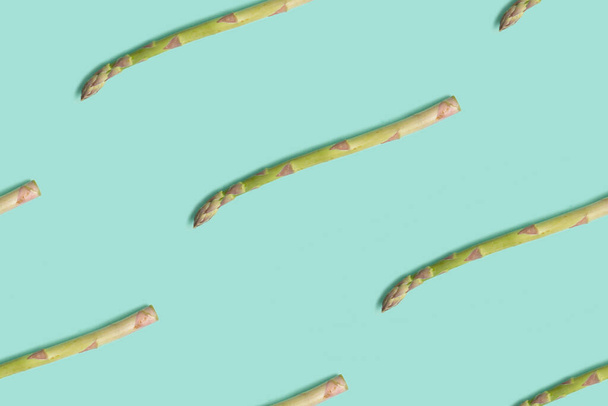 Modello senza cuciture da lance di asparagi naturali fresche su uno sfondo verde pastello. Posa piatta
. - Foto, immagini