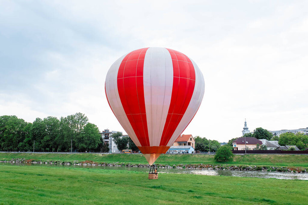 Mavi gökyüzünde balon. Mavi bulutlu gökyüzünde kırmızı balon ve yeşil çimenlik. - Fotoğraf, Görsel