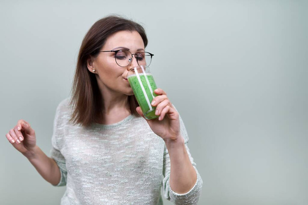 Mature woman with green vegetable smoothie drink, healthy vegan diet, woman drinking juice - Foto, Imagem