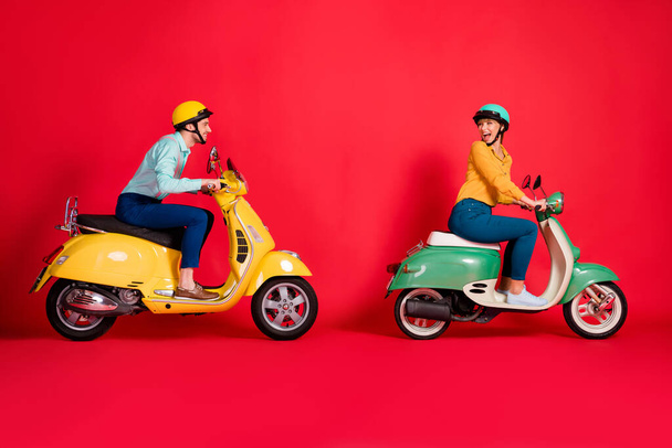 Profile side view of her she his he nice attractive positive cheerful cheery couple riding moped having fun time fast speed racing isolated on bright vivid shine vibrant red color background - Valokuva, kuva