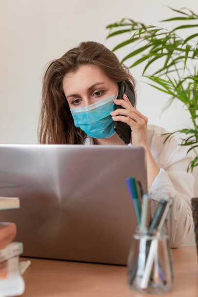 Mujer en cuarentena por Coronavirus usando máscara protectora y trabajo inteligente. Covid-19, epidemia. Trabajo desde casa
 - Foto, imagen