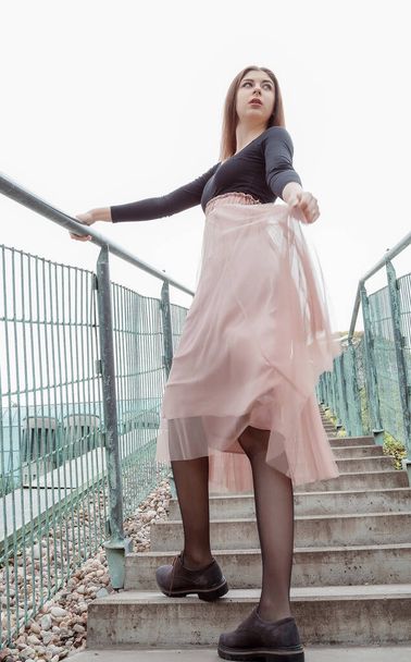 Beautiful girl in a black blouse and pink skirt climbs the stairs up. Young pretty woman walking up the stairs in the city. BUW. Warsaw. - Fotoğraf, Görsel