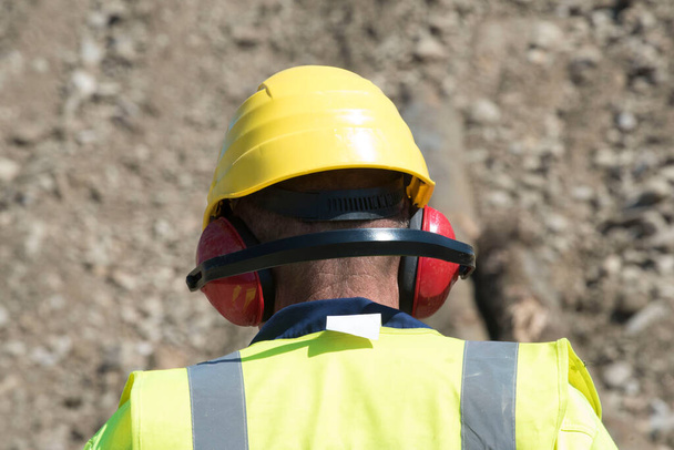 ヘルメットと聴覚保護を身に着けている建設現場の労働者 - 写真・画像