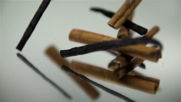 Zimt und Vanillestangen fallen auf Spiegel auf weißem Hintergrund - Filmmaterial, Video