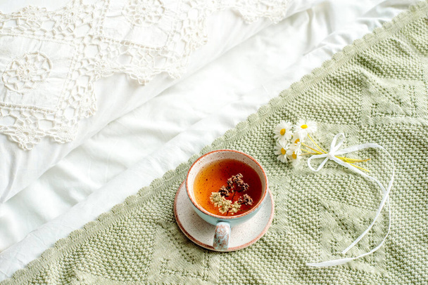 cup of natural herbal tea from mint and lemon balm in bed,morning close up. Cozy atmosphere.Diagonal lace,cotton white blanket,summer daisy flowers.breakfast.Provence and retro style. - Photo, image