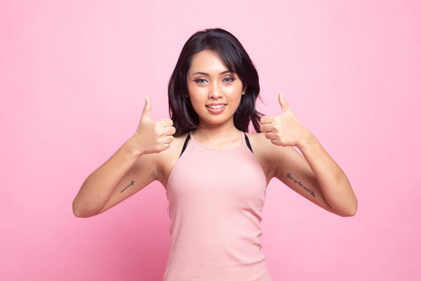 Young Asian woman show two thumbs up on pink background - Fotoğraf, Görsel