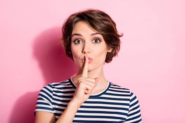 Closeup photo of funny pretty lady hold finger on lips asking roommates be silent shhh wear casual striped white blue t-shirt isolated pastel pink color background - Foto, Imagem