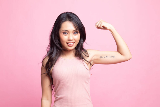 Beautiful young Asian woman flex bicep on pink background - Foto, Bild