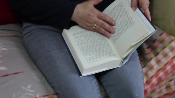 Uma mulher folheando através de um livro sentado confortavelmente no sofá
. - Filmagem, Vídeo