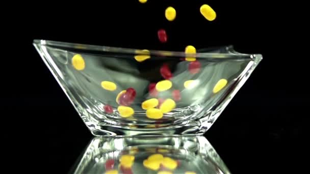 Candy is falling into glass on black background - Footage, Video