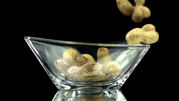 Amendoins estão caindo em vidro no fundo preto em câmera lenta
 - Filmagem, Vídeo