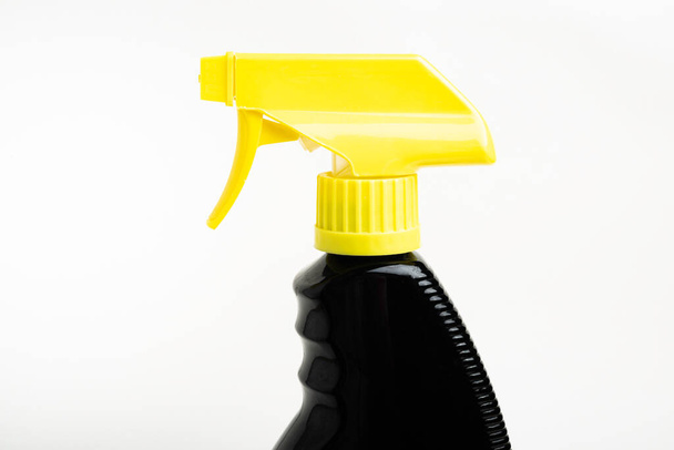 A close-up of the top portion of a black and yellow liquid spray plastic dispenser bottle set on a plain white background. - Zdjęcie, obraz