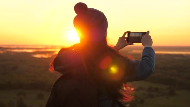 Sağlıklı, neşeli bir kadın şafak vakti seyahat eder ve doğayı telefonla fotoğraflar. Özgür Genç Kız Turist blogcusu, dağların tepesinde güzel manzaralı akıllı bir telefon kullanarak bir selfie videosu kaydediyor.. - Video, Çekim