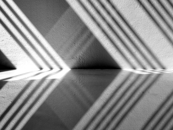 Luz abstracta y sombra del hierro forjado se refleja en la pared de hormigón y suelo de baldosas en la habitación
. - Foto, Imagen