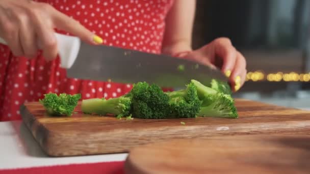 Close up shot of a woman cuting healthy vegetables on a wooden cutting board in a modern kitchen with a big knife - Metraje, vídeo
