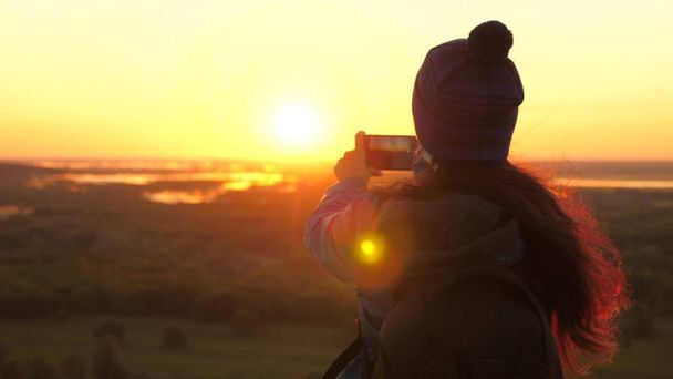 Zdrowa, wesoła kobieta podróżuje o świcie i fotografuje naturę przez telefon. za darmo Młoda dziewczyna turysta blogger nagrywa selfie wideo na szczycie gór za pomocą smartfona z pięknym krajobrazem. - Zdjęcie, obraz