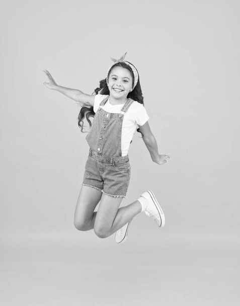 Jump of happiness. small girl jump yellow background. full of energy. Active girl feel freedom. Fun and relax. feeling free. carefree kid on summer holiday. time for fun. retro beauty in mid air - Zdjęcie, obraz