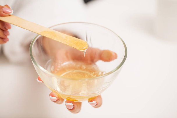 Woman holding a bowl of wax for depilation and skin care - Photo, Image