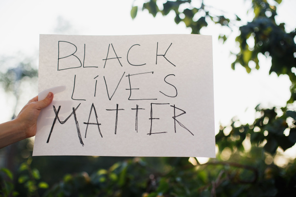 Frau hob Hände und zeigte Zeichen "Black lives matter". Kein Rassenwahn. Schluss mit Raserei. Vor dem Hintergrund von Bäumen und Sonnenlicht. - Foto, Bild