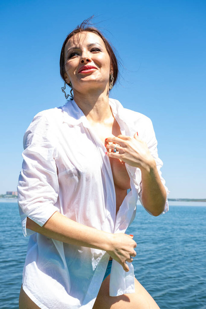 Дівчина в мокрій білій сорочці на фоні моря
 - Фото, зображення
