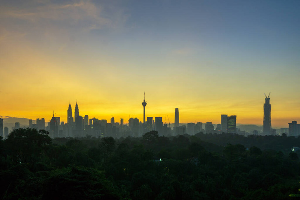 Kuala Lumpur şehir merkezinde muhteşem bir gün doğumu. Modern silueti 451 metre yüksekliğindeki KLCC, İslami motifli cam ve çelik kaplı bir çift gökdelen tarafından yönetiliyor.. - Fotoğraf, Görsel