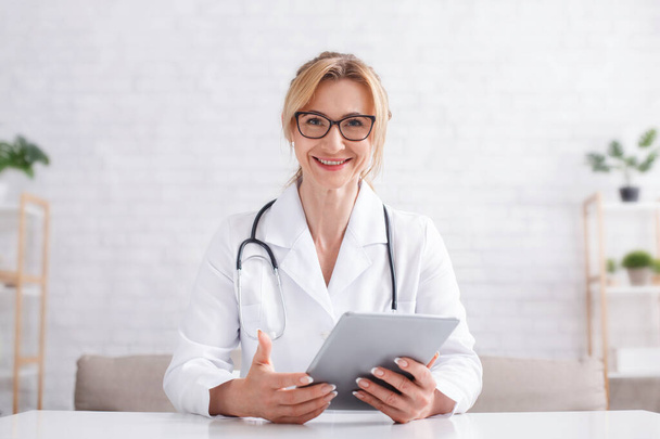 Доктор и цифровые технологии. Женщина держит планшет в руках в медицинском кабинете
 - Фото, изображение