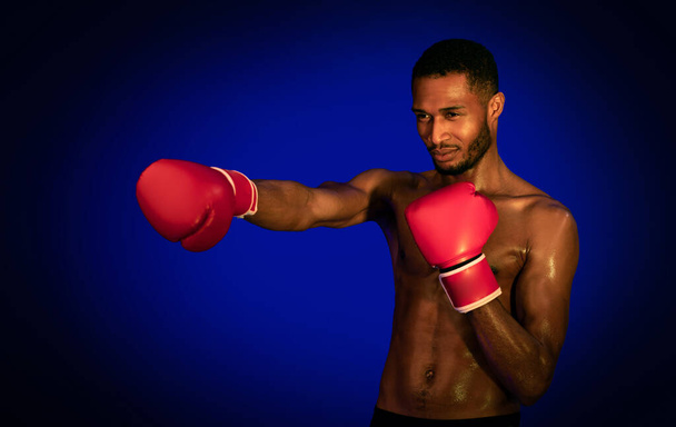 African American Boxer Boxing Wearing Gloves Standing Over Blue Background - Foto, imagen